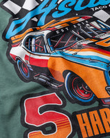 Taco Gear Tres de Asada Racing t-shirt featuring vintage racecar graphic, bold “Harina y Maíz” text, and checkered flag design on black and green tees.