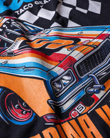 Taco Gear Tres de Asada Racing t-shirt featuring vintage racecar graphic, bold “Harina y Maíz” text, and checkered flag design on black and green tees.