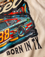 Taco Gear Always Fresh Racing t-shirt with vintage skull and racecar graphic, bold “Born in TX” text, and retro motorsport design on black and sand tees.